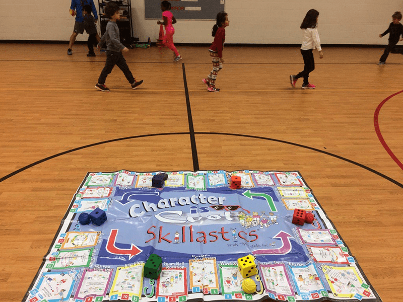 Students exercising and playing Character is Cool Skillastics on gym floor.