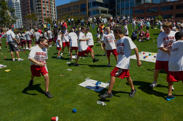 100 students playing Skillastics outdoors at physical activity event.
