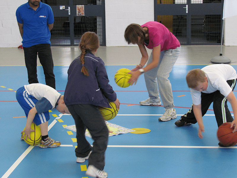 Students surrounding Basketball Skillastics mini mat completing Basketball drills