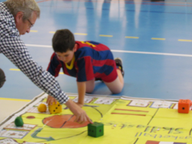 Instructor helping boy on Basketball Skillastics oversize mat on gym floor