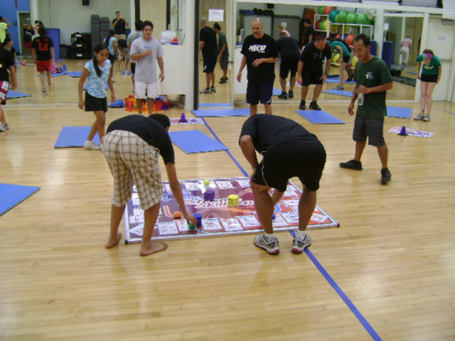 Mixed ages playing Fitness Xtreme Skillastics on wood floor