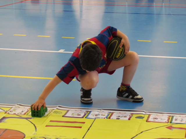 Boy moving beanbag marker on Basketball Skillastics oversize mat in  After School Program