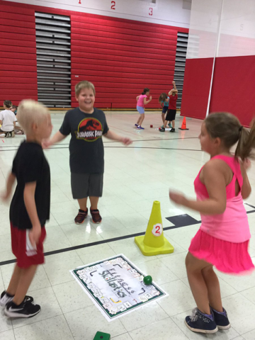 Students exercising and playing Fitness Skillastics on gym floor.