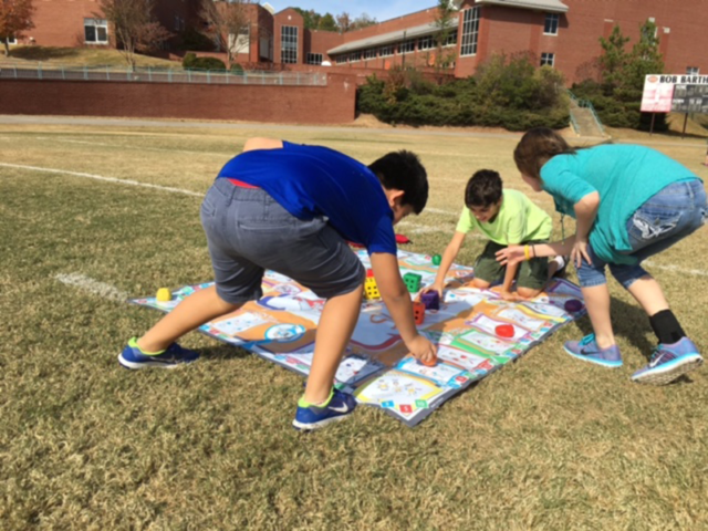 Students exercising and playing Skillastics on grass in After School Program