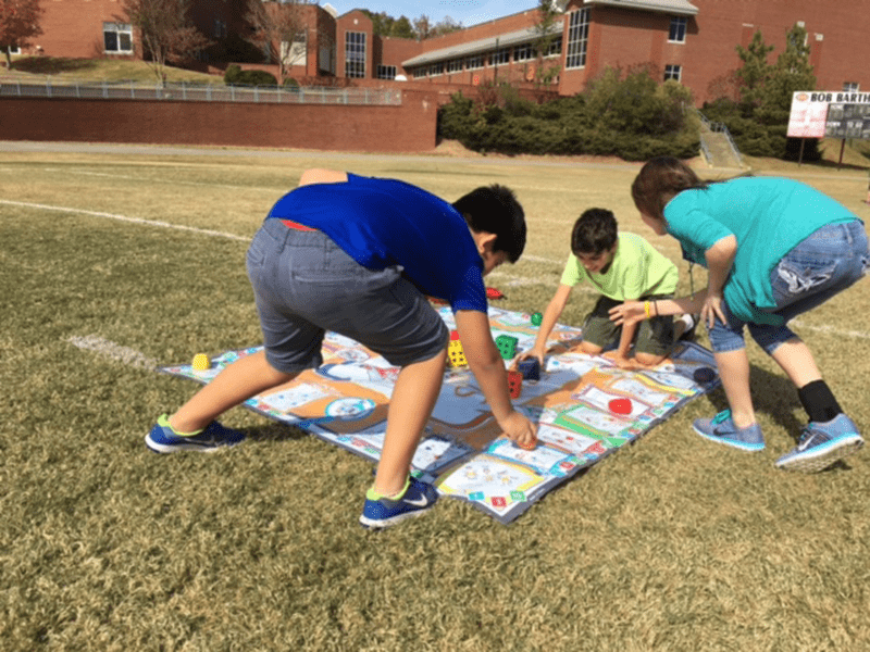 Students exercising and playing Skillastics on grass in After School Program